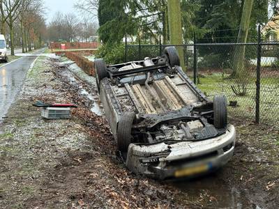 Auto slipt op gladde weg en belandt ondersteboven in sloot bij De Mortel, bestuurster gewond