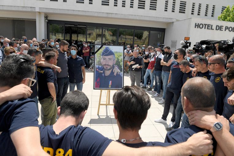Politiemensen in Avignon staan rond het portret van de begin mei doodgeschoten collega Éric Masson. 
 Beeld AFP