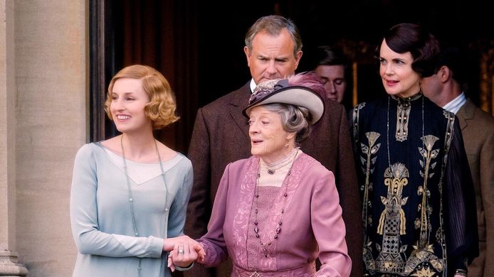 Downton Abbey keert terug met een nieuw seizoen, maar er is twijfel ontstaan of Maggie Smith (centraal met hoed) weer meedoet.