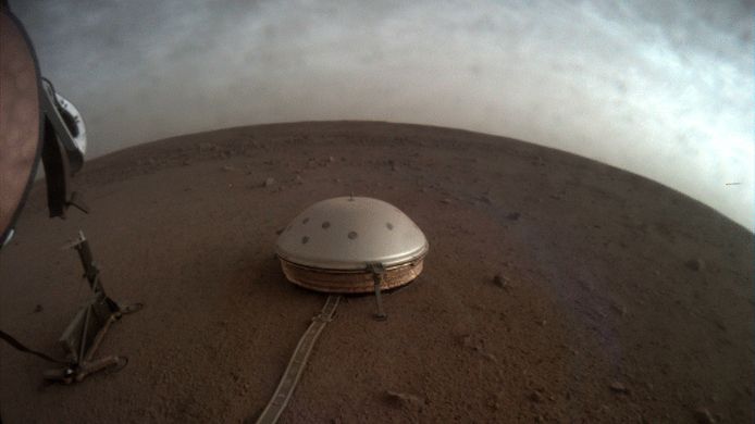 Stofwolken rollen over de met koepel bedekte seismometer van de InSight-lander op Mars. Het bevingsmeetapparaat biedt een blik op de binnenkant van de planeet en onthulde al dat Mars een verrassend dunne korst en gesmolten kern heeft.