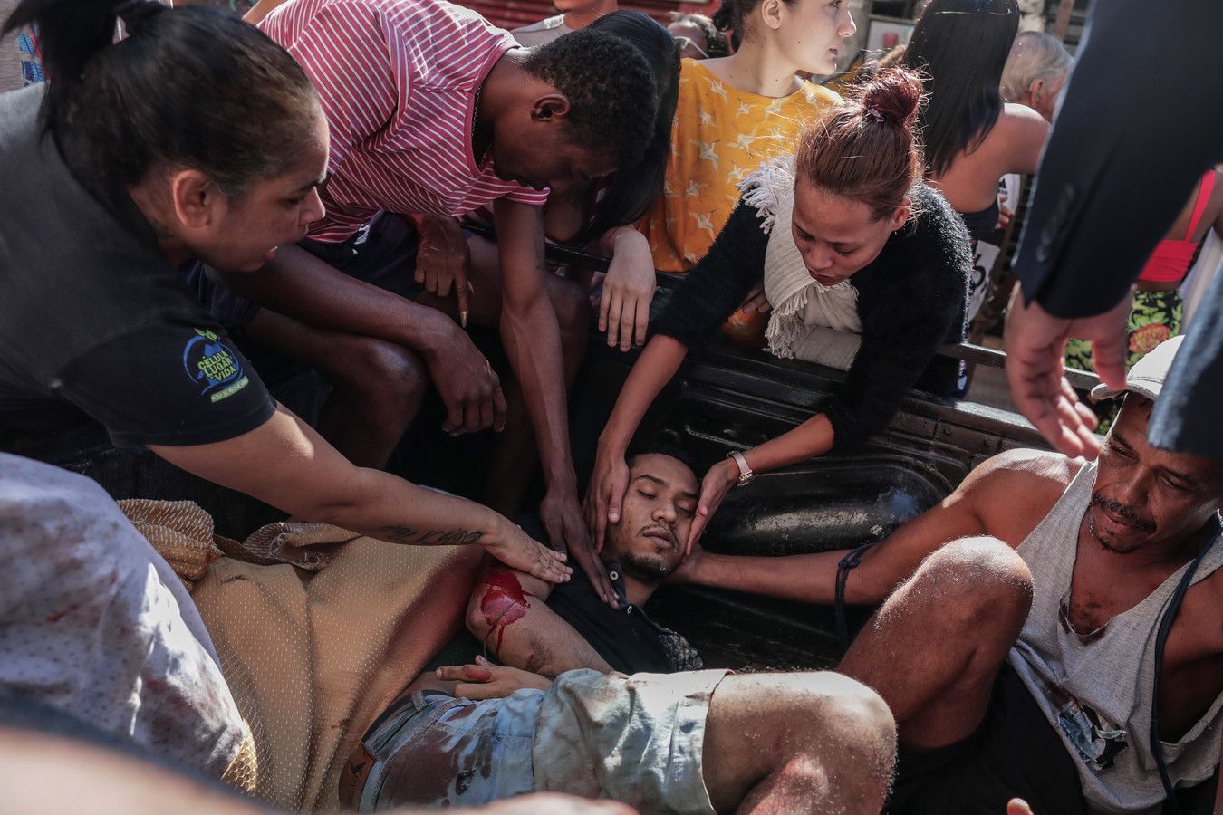 Een gewonde man wordt door buurtgenoten omringd in Complexo do Alemão, Rio de Janeiro.