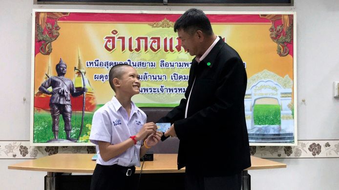 Mongkol Boonpiam, een van de geredde voetballertjes, krijgt een Thaise identiteitskaart van de lokale sheriff Somsak Kunkam.