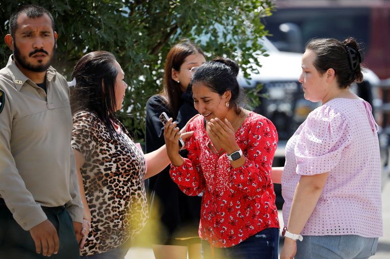 Een vrouw barst in tranen uit buiten het buurthuis waar kinderen werden opgevangen na de massamoord op de basisschool.  Beeld Marco Bello / REUTERS