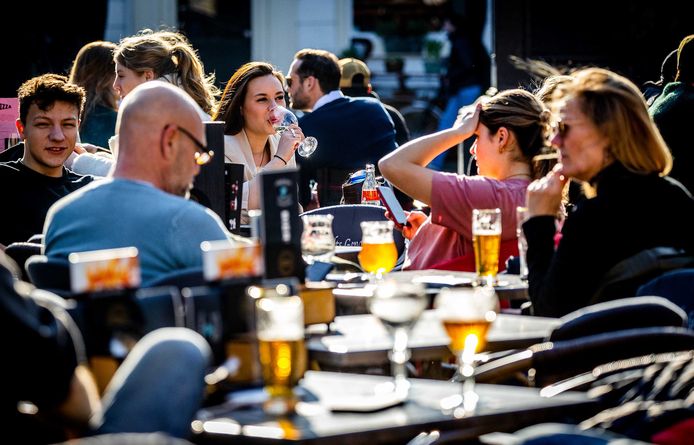 Mensen genieten op terras van het zonnige weer, beeld ter illustratie