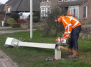 Een medewerker van Heijmans is aan het werk om de omgezaagde paal mee te nemen