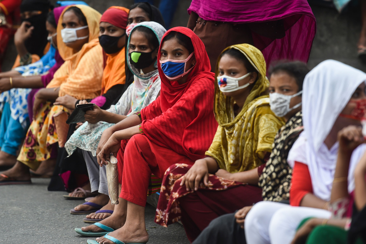 Textielwerkers in Dhaka, Bangladesh, blokkeren de weg uit protest tijdens de lockdown van de overheid in april. Ze eisen dat ze betaald worden. Beeld AFP