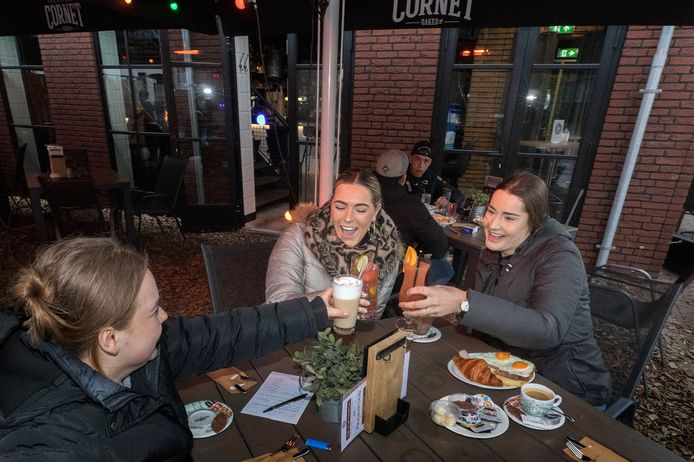Iris van den Biggelaar, Romy Hoogers en Romy Smits (vlnr) zijn vanochtend om 6 uur neergestreken op het terras van De Vijfhoeck in Helmond en vieren dat met een cocktail. Op de achtergrond Maarten van Kraay en Ryan Lenssen uti Helmond die strak om 6 uur aan het bier zijn gegaan. ,,Daar is het nooit te vroeg voor."