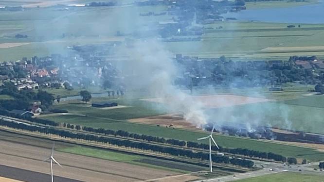 In de brand gevlogen landbouwvoertuig zorgt voor grote rookwolk