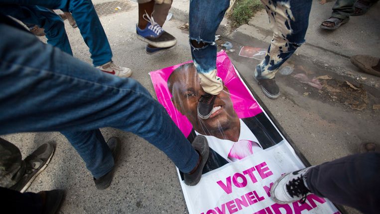 Demonstranten trappen een poster kapot van presidentskandidaat Jovenel Moise - archief. Beeld AP