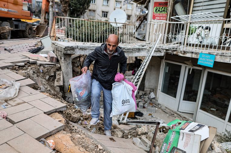 Inwoners uit Hatay halen met gevaar voor eigen leven spullen uit hun beschadigde of ingestorte huizen.  Beeld ANP / EPA
