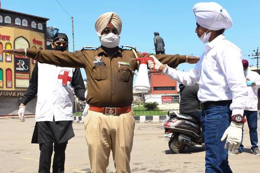 Een vrijwilliger besprenkelt een politieman met een desinfecterend middel in de deelstaat Punjab.
