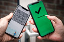 Een telefoon met een groen vinkje in de CoronaCheck app.