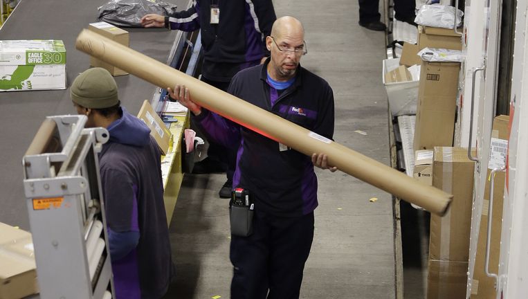 Werknemers van FedEx vullen in New York hun vrachtwagens met spullen van de lopende band. Beeld ap