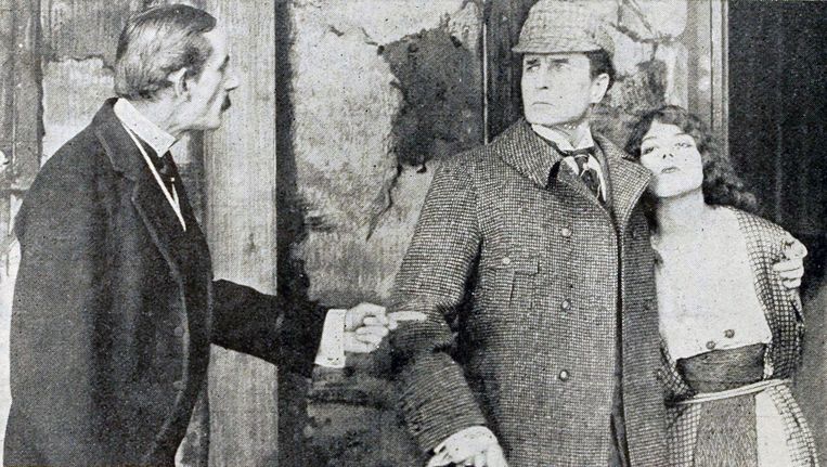 William Gillette (midden) als Sherlock Holmes in de gelijknamige film. Beeld Wikipedia