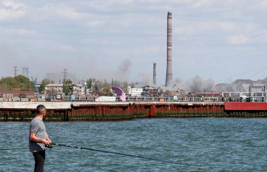 Een vissers in de haven van Marioepol kijkt naar de belegerde Azovstal-fabriek op de achtergrond. (29/04/2022)