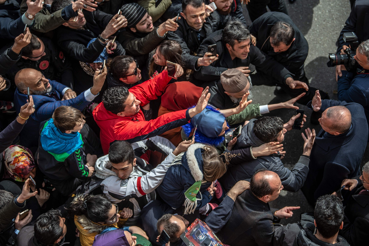 Turks president Recep Tayyip Erdogan (r.) ontmoet mensen op straat bij het verlaten van een stembureau tijdens de lokale verkiezingen in Istanbul in maart.  Beeld AFP