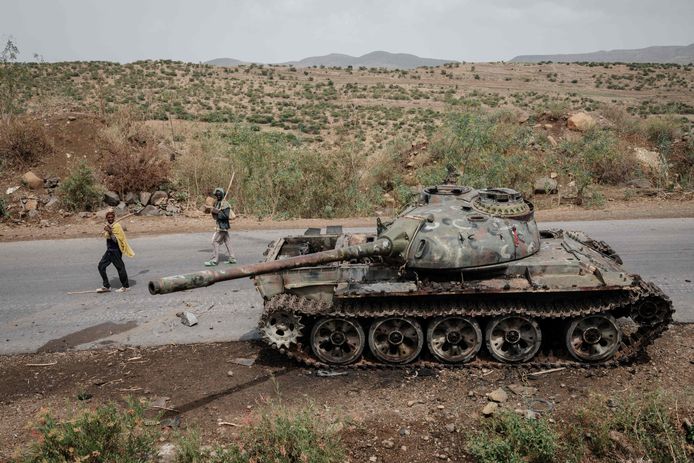 Ehtiopiërs wandelen langs een achtergelaten tank in de regio Tigray, in het noord van Ethopië.