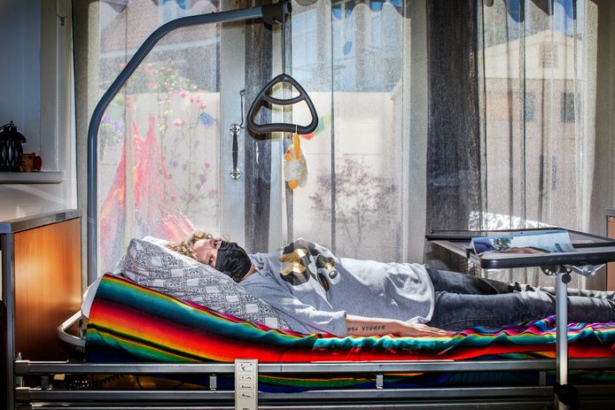 Linda van der Horst ligt in een ziekenhuisbed in haar woonkamer te wachten op medische behandeling.