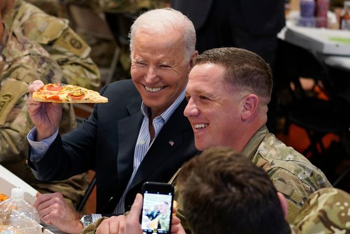 President Joe Biden holds a piece of pizza as he posed for a photo during a visit with members of the 82nd Airborne Division at the G2A Arena, Friday, March 25, 2022, in Jasionka, Poland. (AP Photo/Evan Vucci)