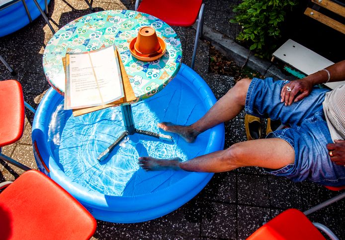 Een man zit met zijn voeten in een zwembadje op een terras.