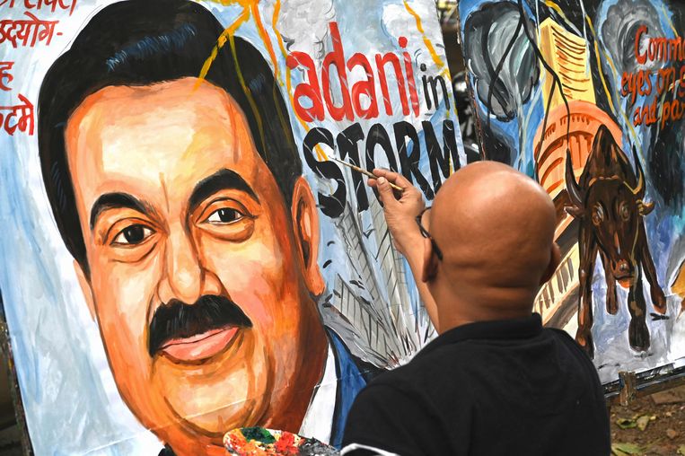 Een straatkunstenaar in Mumbai probeert de crisis te vangen waarin de tot voor kort rijkste man van India zich momenteel bevindt.   Beeld AFP