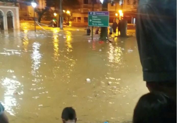 Le persone stanno nelle strade allagate nella città turistica di Petropolis, in Brasile.