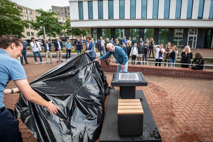 Wethouder Arjen Maathuis (l), grootmeester Lucas van Foreest en voorzitter Ton van Manen van de schaakvereniging Almelo onthullen de schaaktafel.