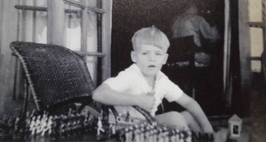 Theo Doorman speelt met tinnen soldaatjes in hun huis in Soerabaja, 1941. Op de achtergrond is vader Karel aan het werk.