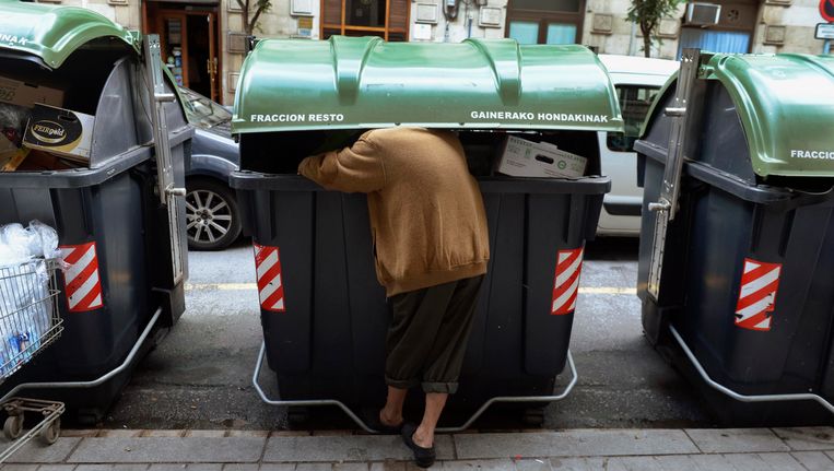 Een man zoekt naar eten in een afvalbak in Bilbao, Spanje. Beeld Reuters