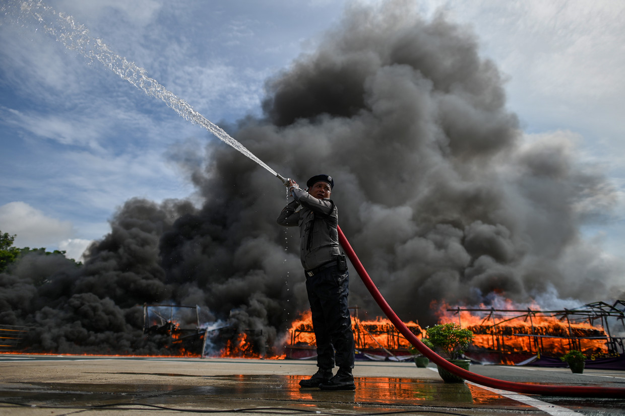Een brandweerman in de My­an­ma­rese stad Rangoon houdt het vuur onder controle van een enorme berg drugs die wordt vernietigd. 
