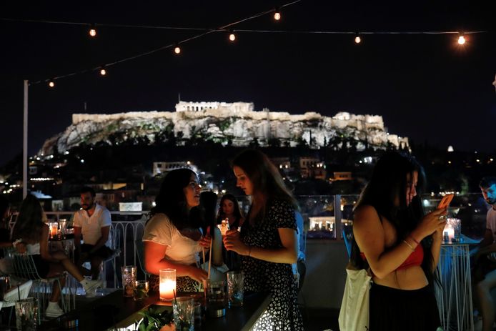 Bezoekers van een bar in Athene, met op de achtergrond de Akropolis.