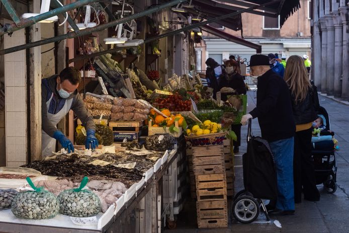 Mensen kopen groenten op een markt in Venetië, Italië.