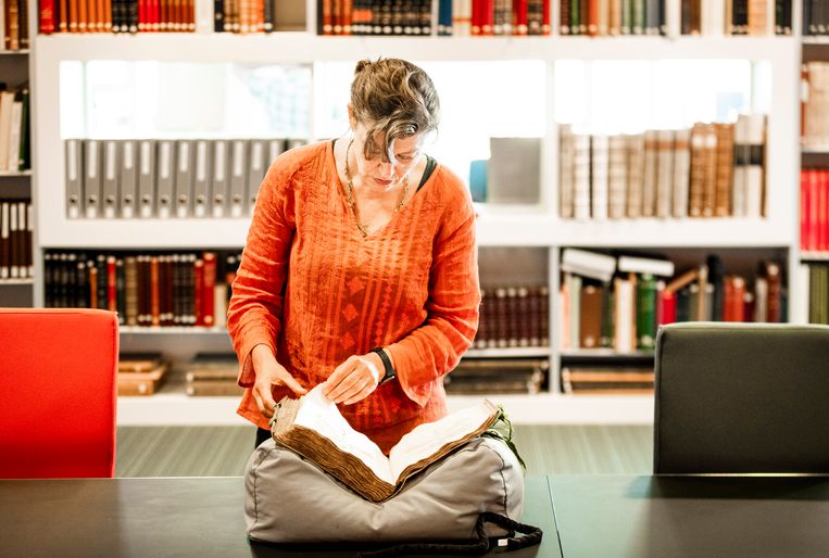 Tinde van Andel bladert door een oud VOC-boek in de Universiteitsbibliotheek in Leiden.  Beeld Freek van den Bergh