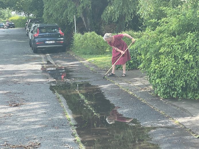 In de Sint-Martemslaan in Kortrijk poetst een buurvrouw de resten van de wateroverlast weg.