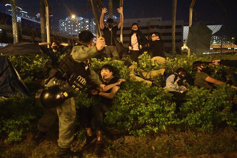 De politie in Hongkong houdt dinsdag studenten aan die proberen te vluchten van de campus van de Polytechnische Universiteit. 
 Beeld AFP