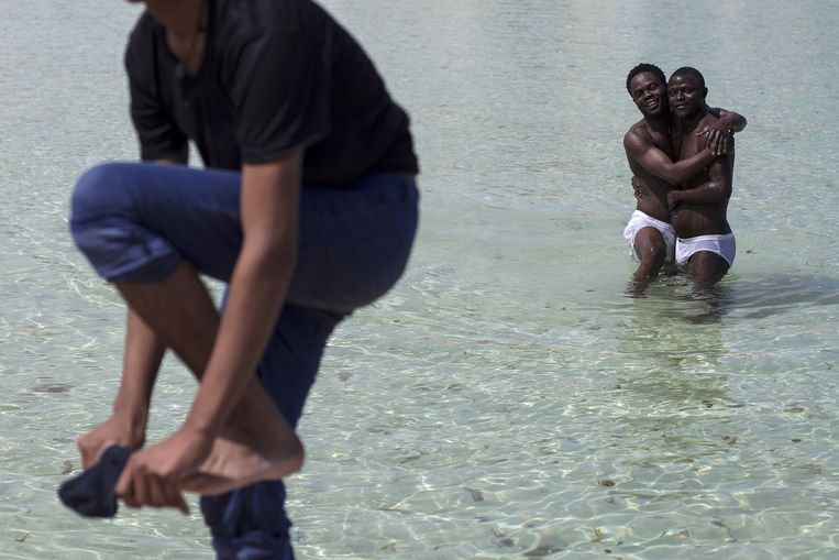 Twee Nigeriaanse bootvluchtelingen nemen een duik in de Middellandse Zee bij het Italiaanse eilandje Lampedusa. Beeld getty