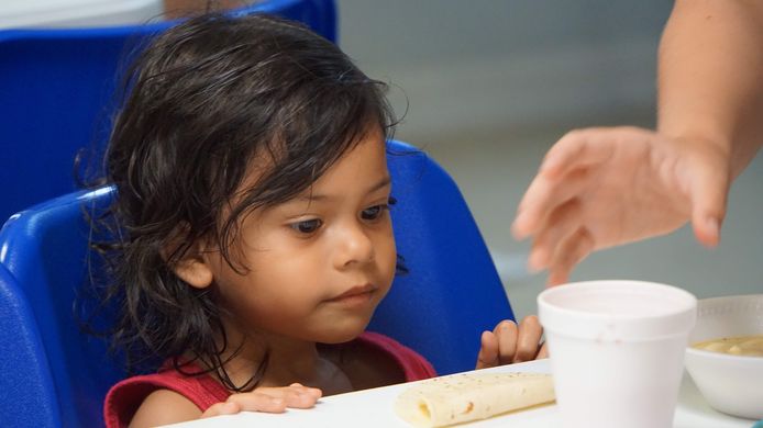 Een meisje krijgt een kopje soep van een vrijwilliger in een migratiecentrum in McAllen in Texas.