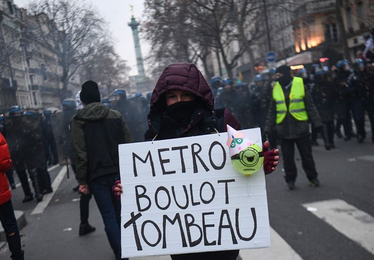 Een demonstrant houdt een bord omhoog met de tekst 'metro, job, graf', een verwijzing naar het Franse gezegde 'metro, boulot, dodo', dat 'eten, werken, slapen' betekent. Beeld AFP