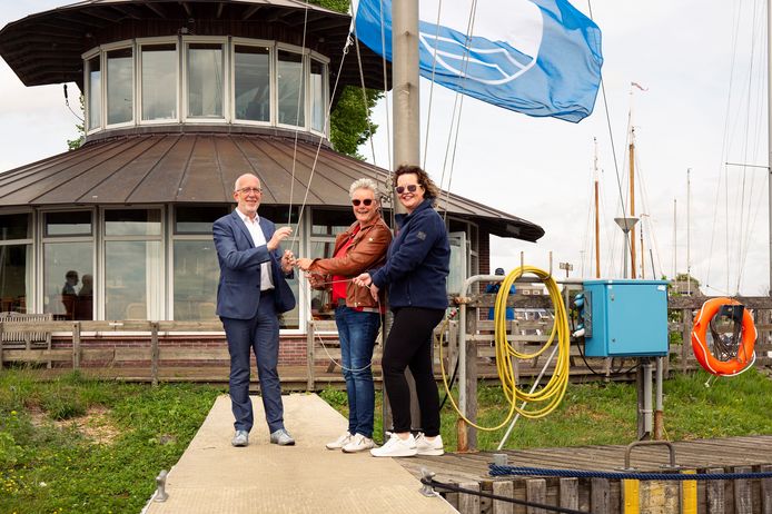 Afscheidnemend wethouder Gerrit Knol hijst de Blauwe Vlag met havenmeester Hilda Verwer van Stichting Recreatiecentrum Zwartewater en Annegreeth Steinbach van Jachthaven de Kranerweer.