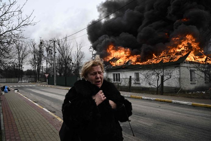 Een Oekraïense vrouw voor een gebombardeerd huis in Irpin, een buitenstad van Kiev. Foto genomen op 4 maart 2022.