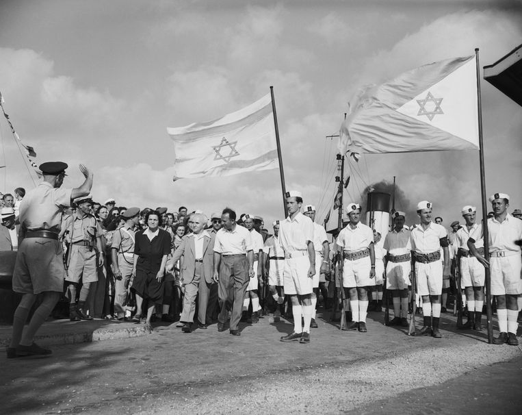 Israëls eerste premier David Ben Gurion (met jasje) zwaait in 1948 de laatste Britse troepen uit die het land verlaten.  Beeld Bettmann Archive