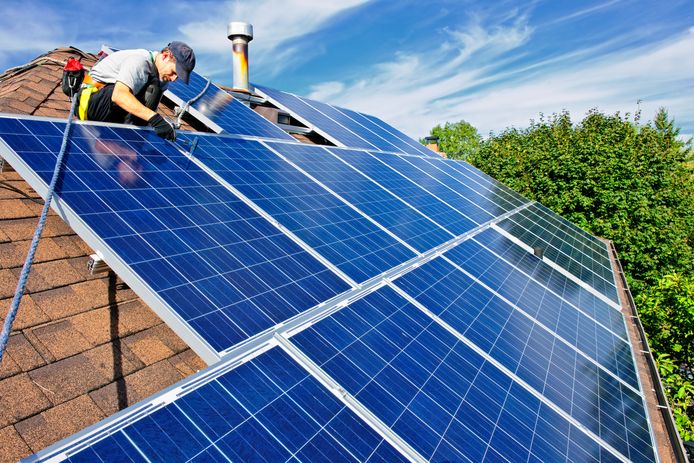 Een arbeider installeert zonnepanelen op een dak.