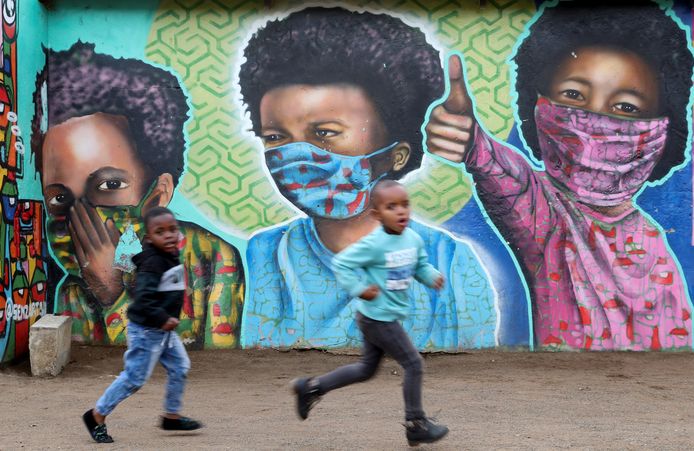 Twee knapen lopen langs een beschilderde muur door Senzart911 in het Zuid-Afrikaanse Soweto.