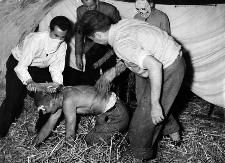 Een ontgroening in 1962 waarbij ouderejaars een ‘feut’ op handen en voeten door smerig stro in een kelder jage. Beeld Collectie Spaarnestad