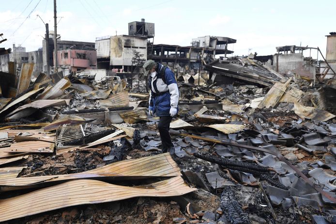 Een man zoekt naar persoonlijke spullen in het puin van zijn huis in Wajima nadat een brand ontstond door de aardbeving.