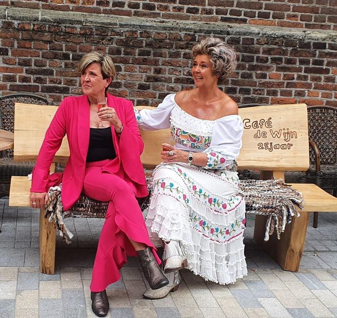 Jolanda (links) en Bernadette op het jubileumbankje dat ze van de vaste bezoekers van café De Wijn kregen.