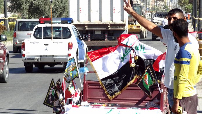 Iraakse burgers delen vlaggen van hun land uit na de overname van Kirkoek door regeringstroepen.