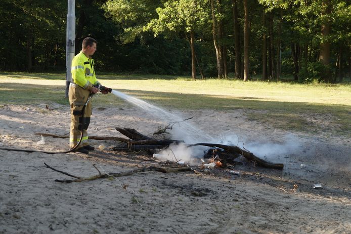 De brandweer doofde de smeulende boomstammen aan de oever van de Roeivijver in Drunen.