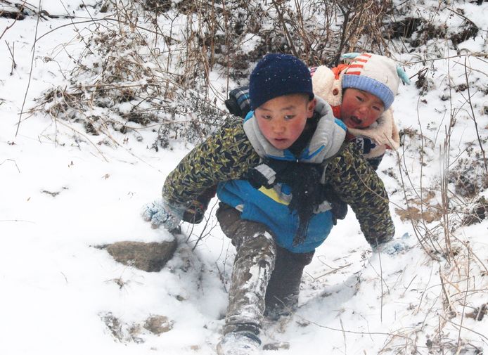 De 9-jarige Chinese Jijue Jizhu loopt met zijn broertje op z'n rug op weg naar de verhuiswagen. Jijue moet samen met zijn familie verhuizen uit hun huidige huis. Ze krijgen een beter huis aangeboden dankzij een regeringsprogramma dat arme mensen helpt aan betere huisvesting. Foto Tian Jianchuan
