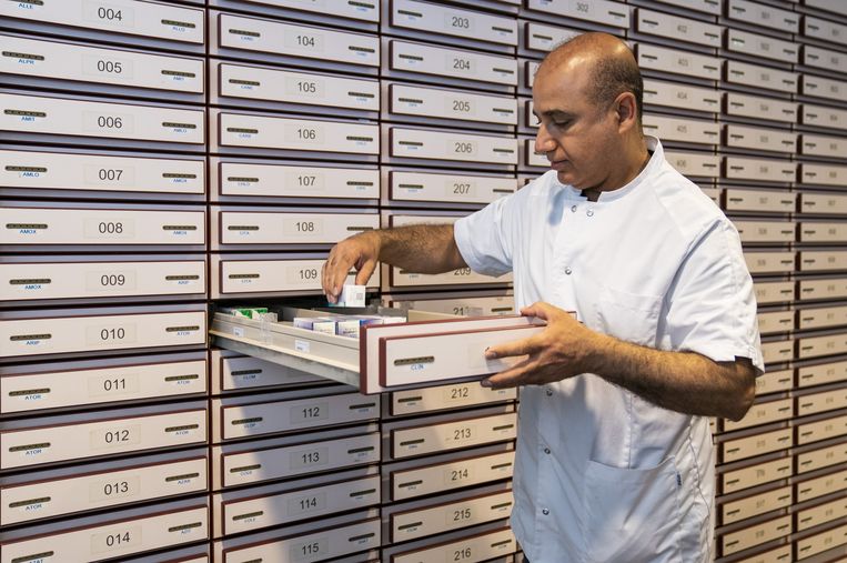 Een apotheekmedewerker bekijkt de medicijnvoorraad in een apotheek. Beeld ANP